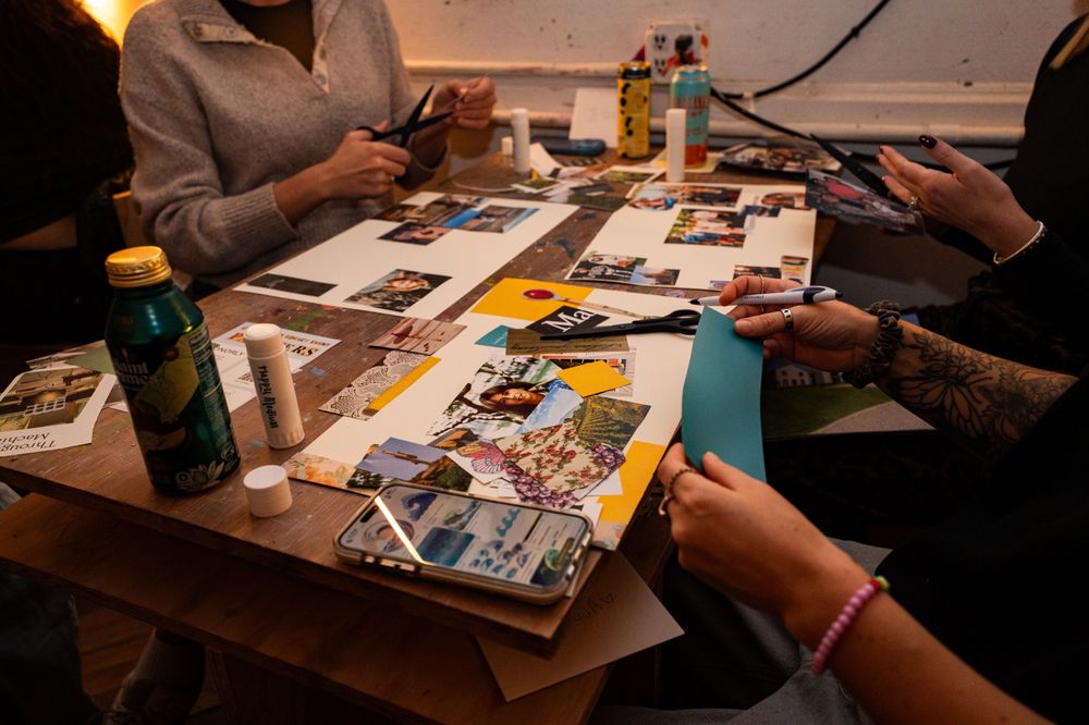 Hands at a table cutting and arranging photographs into a collage.