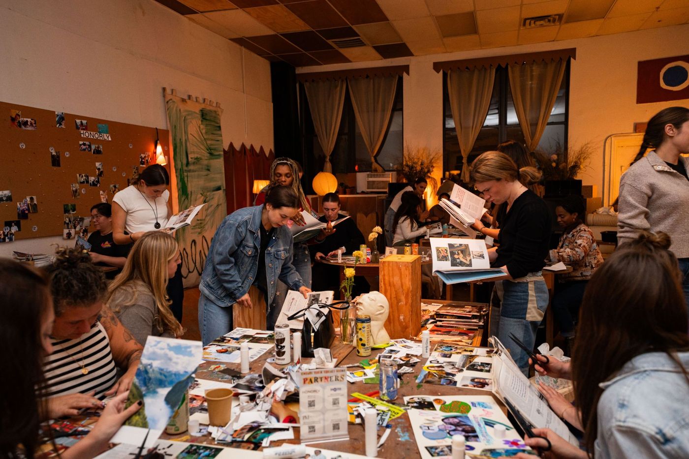 The studio full of people working at long wooden tables under warm lamps.