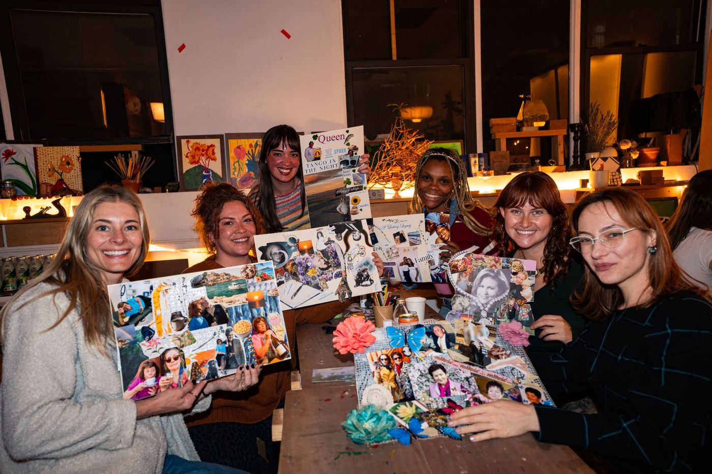 Six guests at a table holding up the Legacy Boards they made.