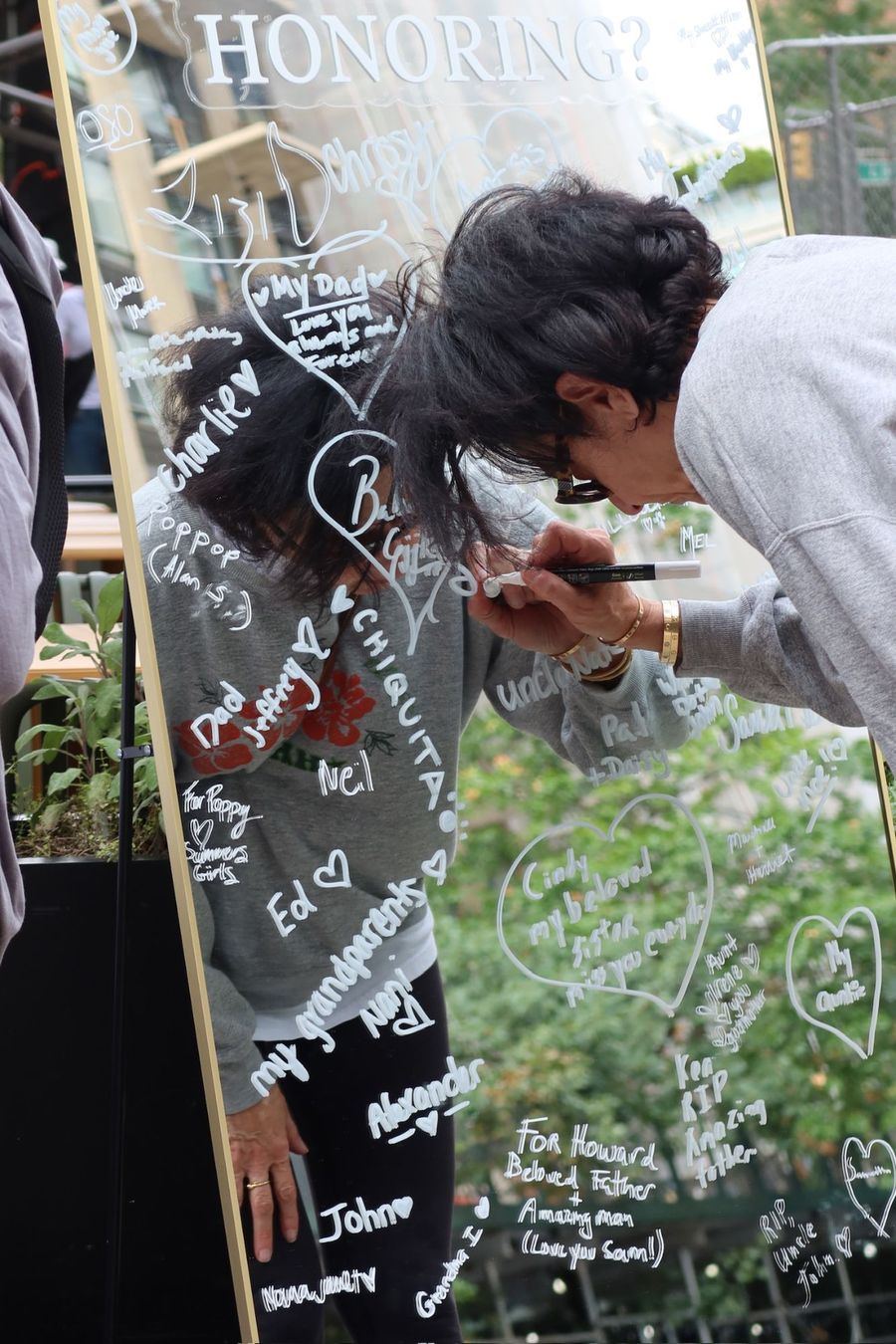 The mirror covered in handwritten names of people being remembered.